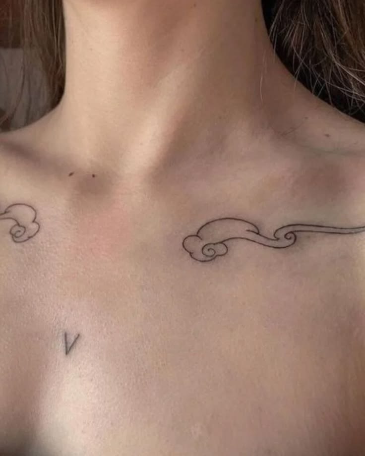Delicate little cloud outlines placed along the collarbone, 
