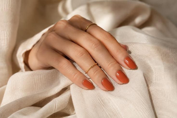 A glossy, softly rounded terracotta manicure gives burnt ora