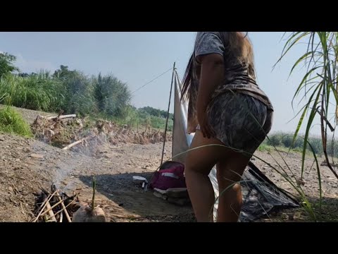 Mother camping on the river bank near the mountains, eating natural products